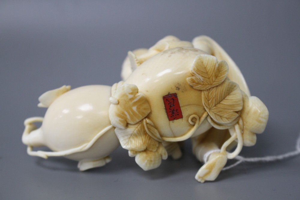 A Japanese Meiji period ivory okimono carved with a man carving a giant gourd, signed, length 10cm, height 7cm